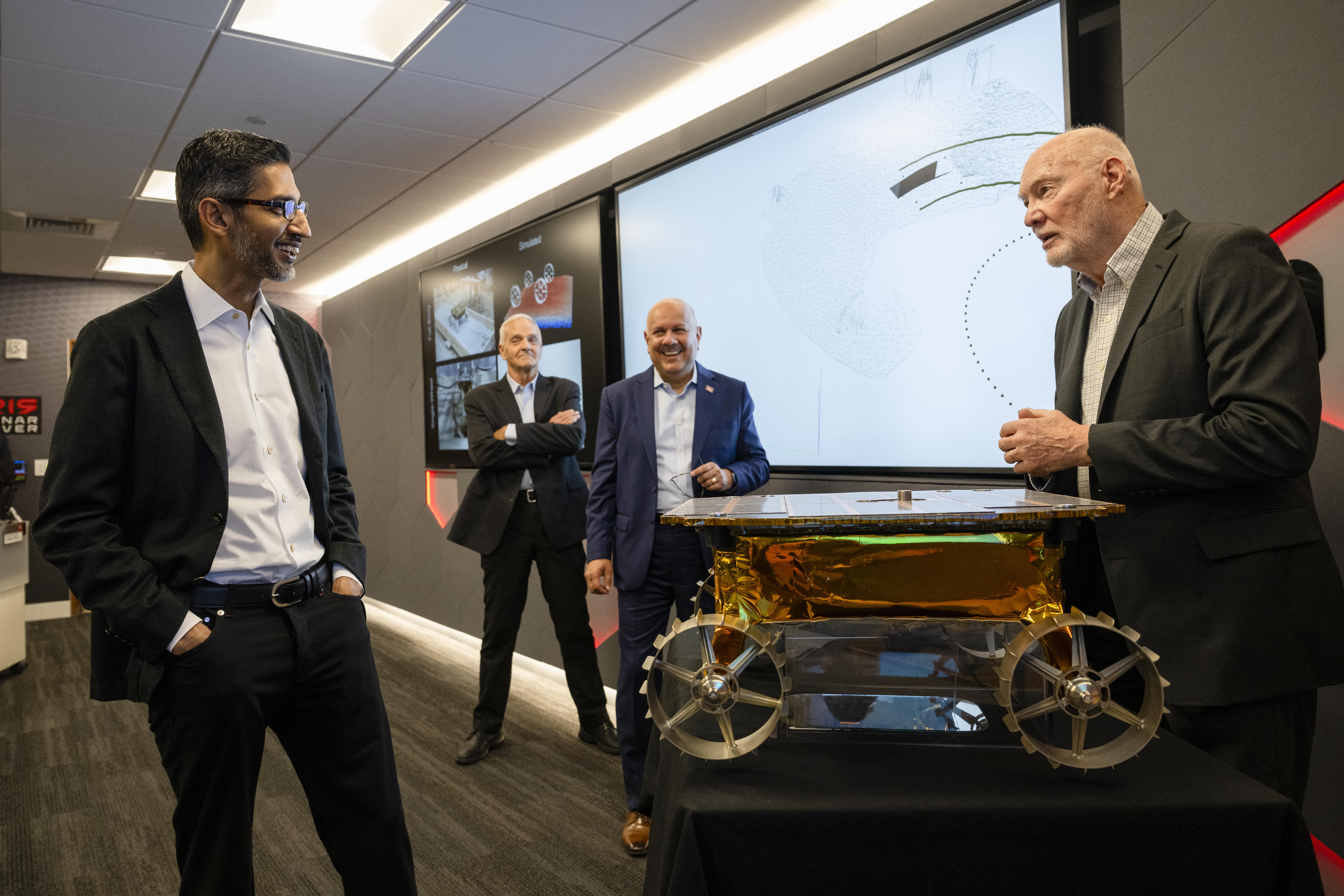 Prof. Red Whittaker (right) in the Robotics Institute, explains the unique fabrication of the Iris rover to Pichai (left) as Jahanian (center) and School of Computer Science Dean Martial Hebert (left of center) listen in.
