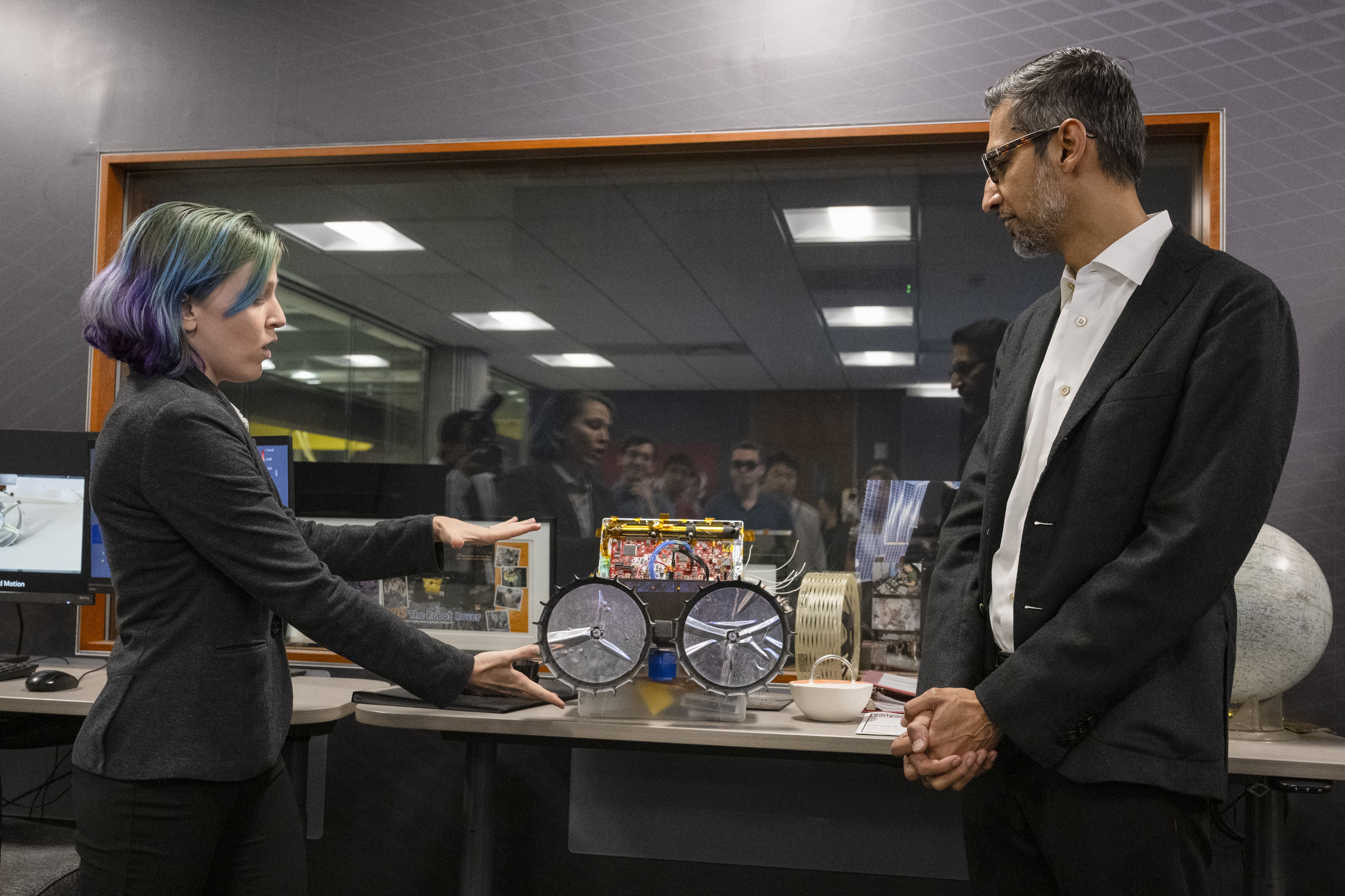 Pichai (right) listens as Raewyn Duvall (left), research associate in the Robotics Institute and commander of the Iris Mission, demonstrates a model of the Iris lunar rover at Carnegie Mellon Mission Control.  