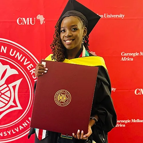 Tanya Akumu holding a diploma in graduation cap and gown