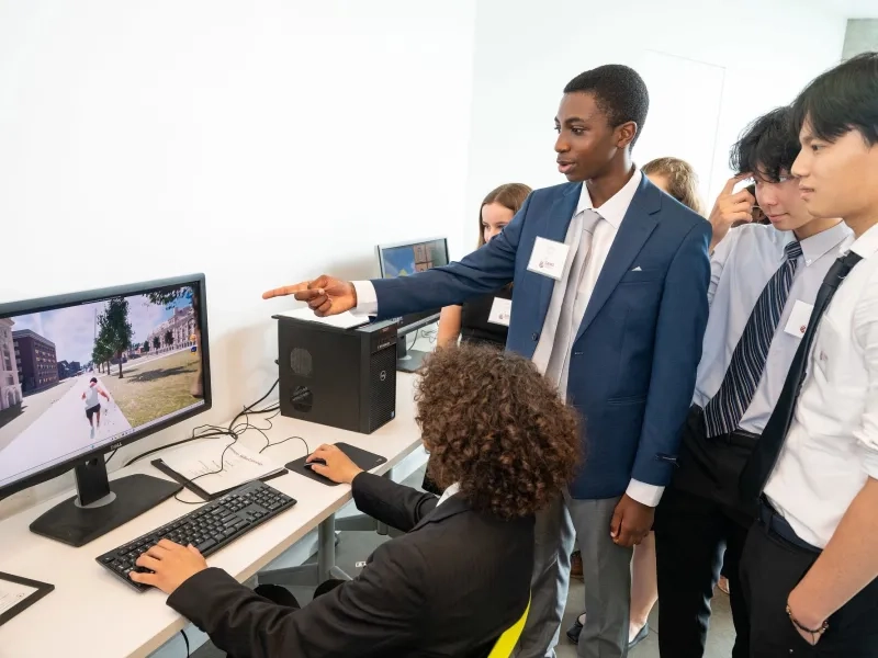 Several students looking at a computer with on pointing at the screen