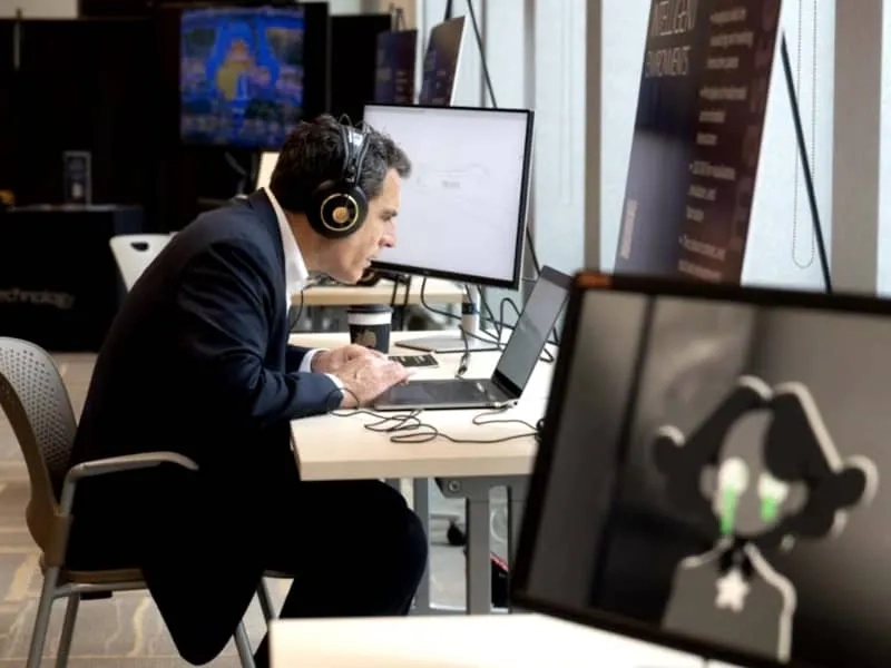 A CMU student sits at their laptop wearing headphones and completing work for a BXA Intercollege degree program