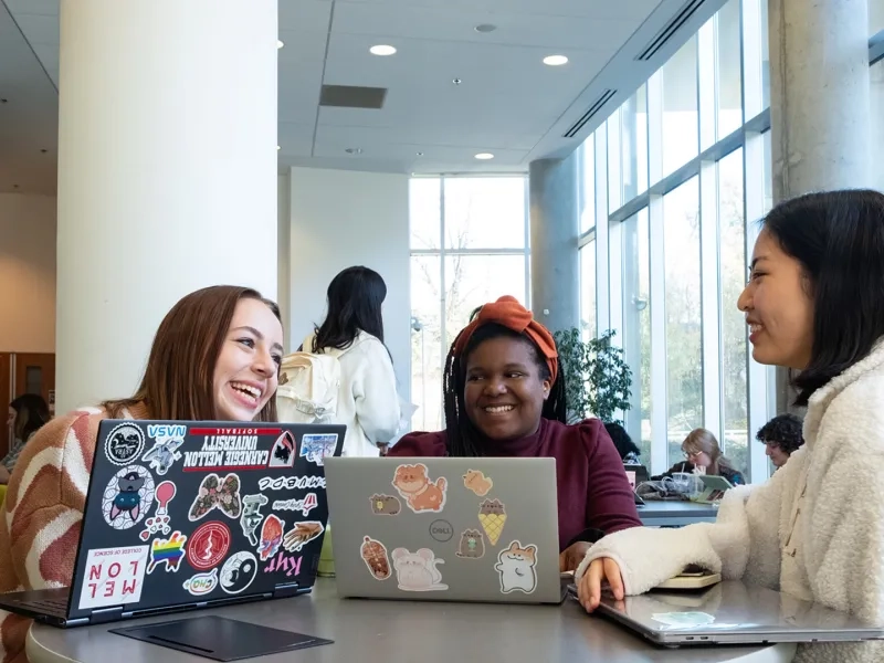 Students sitting at a table with their laptops