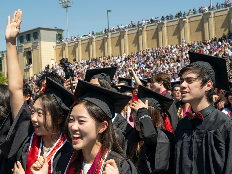 Students wearing caps and gowns outside at commencement