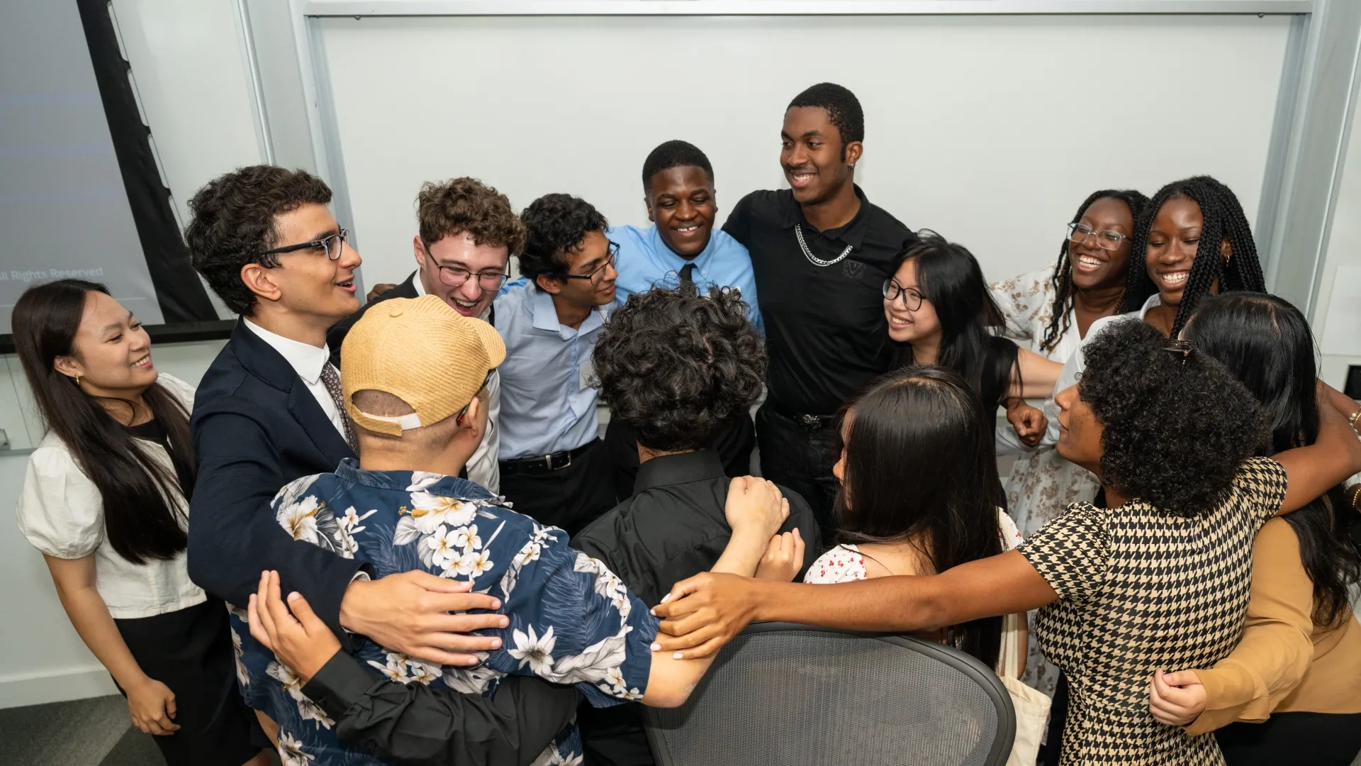 Smiling group of Science and Math Symposium participants hug in a circle.