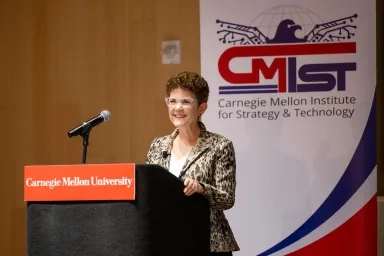 Audrey Cronin standing at a podium in front of a CMIST banner