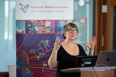 A woman standing at a podium in front of a Humanities Center banner
