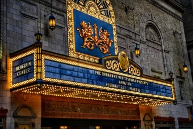 Illuminated marquee of the Benedum Center, showcasing "Hamilton"  with show dates on the ornate facade