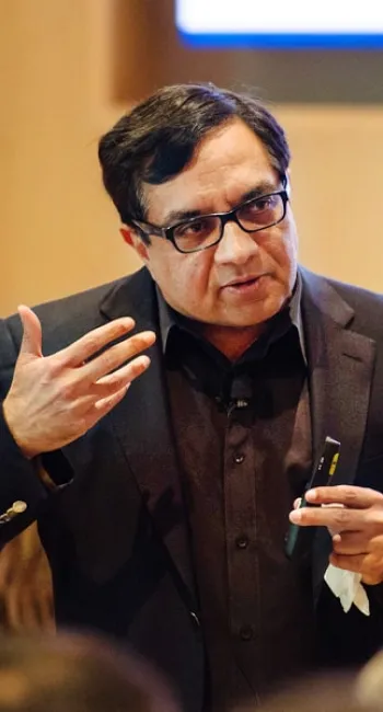 Sridhar Tayur speaking with a microphone in front of a group