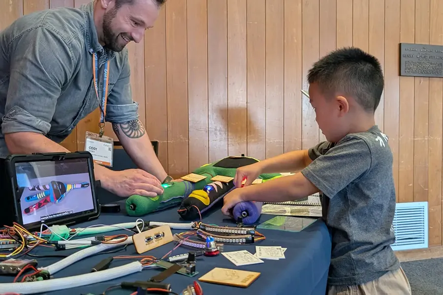 IDeATe Technical Specialist Cody Soska helps a young learner investigate the Plush Neuron